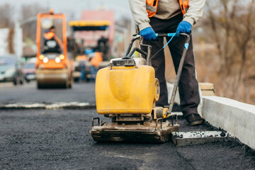 Asphalt vibratory plate compactor. Road service repairs the highway