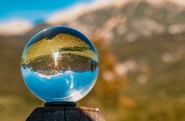 Crystal ball alpine summer landscape shot on a wooden pole near Saalfelden am Steinernen Meer,...