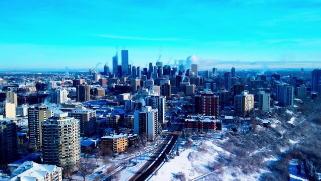 Edmonton Westside residential aerial rise overlooking snow covered winter buildings on bright sunny day flying towards the city center core in the skyline with clear blue sky nobody out in cold 2-2