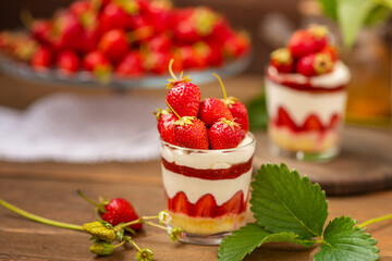 Strawberry dessert in a glass with a decor of cut strawberries standing on a wooden background
