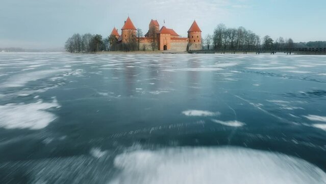 High speed flying drone footage of Trakai Island Castle in Lithuania Europe at winter. Front  entry side view and frozen Lake visible. Filmed with Mavic 3 Cine drone in prores at 50fps.