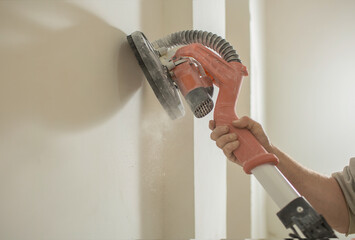 a man  skins the walls with an electric grinder.