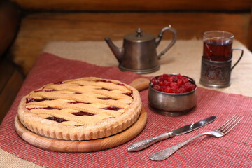 Homemade Danish pie with cherry on the table among the silverware for tea drinking. 