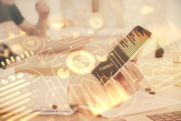 Double exposure of man's hands holding and using a digital device and tech theme hologram drawing. Technology concept.