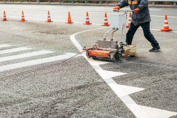 Road workers use scribing machines to painting pedestrian crosswalk on asphalt in the city.
