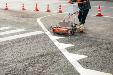 Road workers use scribing machines to painting pedestrian crosswalk on asphalt in the city.