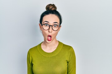 Young hispanic girl wearing casual clothes and glasses afraid and shocked with surprise expression, fear and excited face.