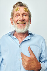Portrait elderly man in a blue shirt bitcoins on the face light background