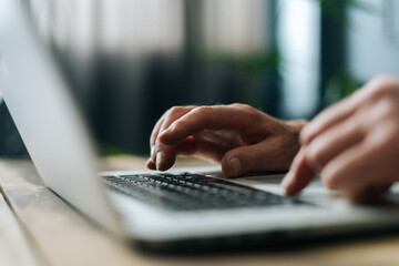 Close-up side view of unrecognizable mature adult man writing text on portable wireless computer...