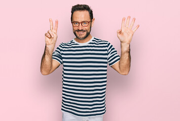 Middle age man wearing casual clothes and glasses showing and pointing up with fingers number seven while smiling confident and happy.