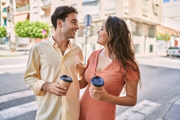 Man and woman couple drinking coffee and hugging each other at street