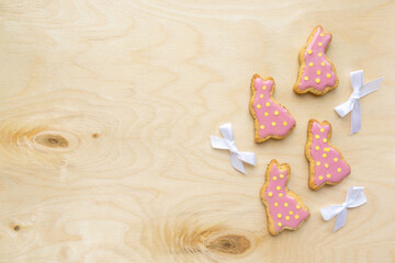 Fototapeta na wymiar Easter flat lay. Homemade cookies in the shape of bunnies with icing and sprinkles on wooden background, space for text