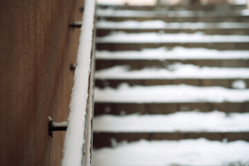 Stair railing and blurred staircase covered with snow