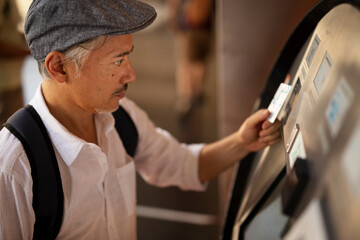 Naklejka na ściany i meble Senior man withdrawing money from credit card. Man typing pin code on keypad of ATM machine..