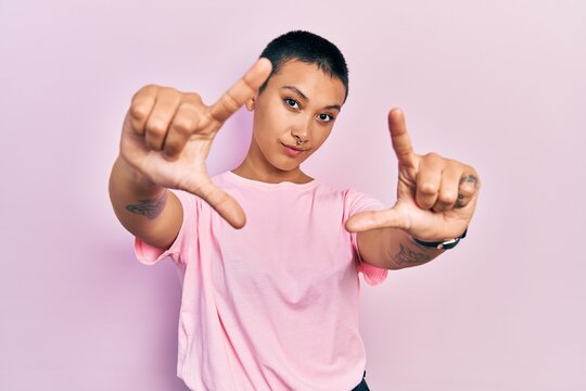 Beautiful hispanic woman with short hair wearing casual pink t shirt doing frame using hands palms and fingers, camera perspective