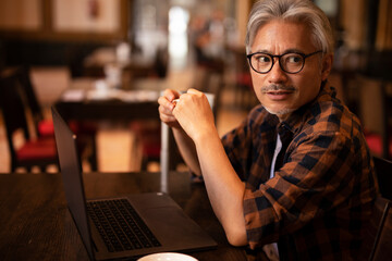 Businessman working on laptop in cafe. Handsome senior man enjoying in fresh coffee.