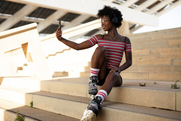 Beautiful African woman with roller skates. Urban sexy girl taking selfie photo
