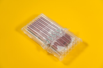 Close-up view stock photography of object packed in bubble plastic protective from cracks wrap laying isolated on bright yellow background