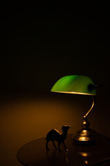 the green lamp on the table illuminates the camel figure
