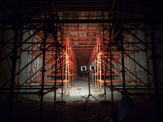 Interior of a bridge deck under construction supported by scaffolding, illuminated by spotlights