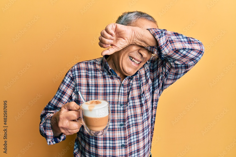 Poster Handsome senior man with grey hair drinking a cup coffee smiling cheerful playing peek a boo with hands showing face. surprised and exited