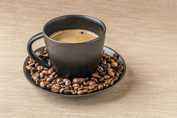 aromatic freshly brewed coffee in a black ceramic cup and coffee beans on a burlap cloth