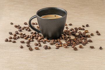 aromatic freshly brewed coffee in a black ceramic cup and coffee beans on a burlap cloth