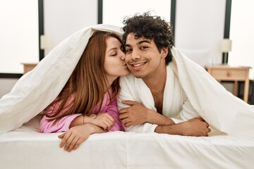 Young couple covering with bedsheet lying on the bed at bedroom.