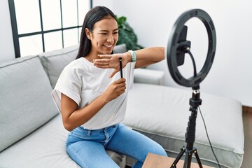 Fototapeta na wymiar Young latin woman smiling confident recording makeup tutorial at home