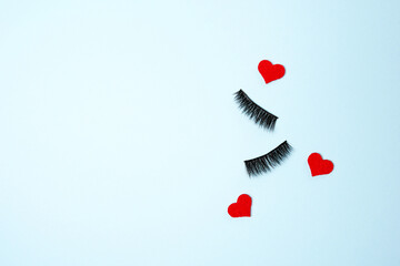 hearts with false eye lashes on blue background with copy space