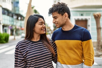 Young latin couple smiling happy and hugging at the city.