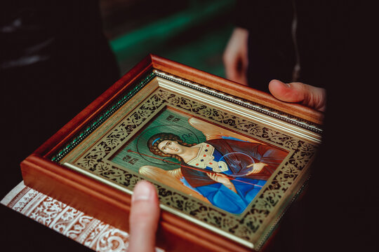 a woman holds an Orthodox icon of the guardian angel in her hands