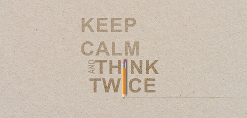 Keep calm and think twice on brown recycled paper background with an orange pencil