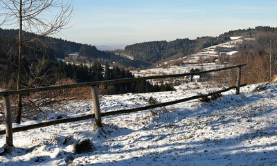 Zimowy górski krajobraz z fragmentem ogrodzenia.