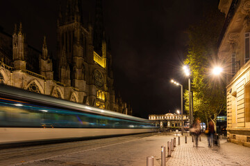 Fototapeta na wymiar Tram passing Bordeaux Cathedral at night in New Aquitaine, France