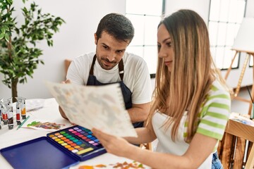 Obraz premium Two students smiling happy painting sitting on the table at art school.