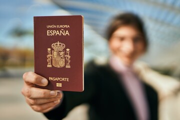 Young beautiful businesswoman smiling happy holding spainish passport at the city.