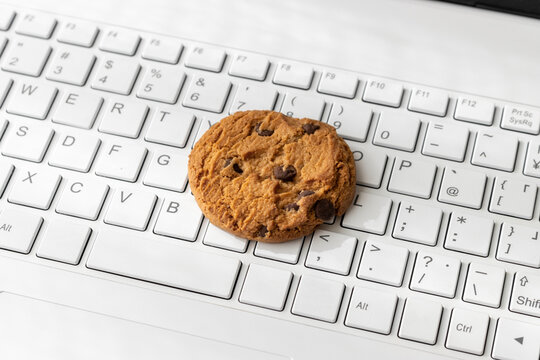 ノートパソコンのキーボードとクッキー。デジタルデバイスのCookieイメージ