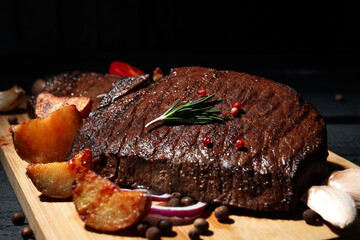 Concept of tasty food with beef steaks on dark wooden table