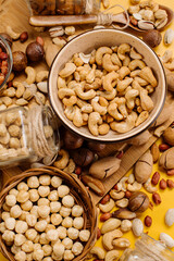 Mix of different types of dried nuts in compositions on a yellow background. Top view. Flat lay