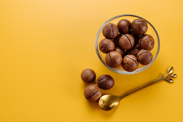 Dry macadamia nuts on a saucer on a yellow background