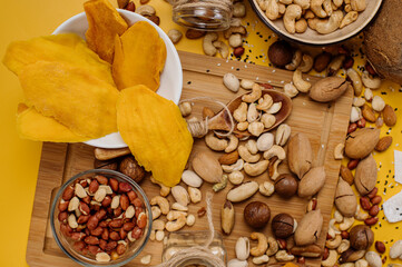 Mix of different types of dried nuts in compositions on a yellow background. Top view. Flat lay