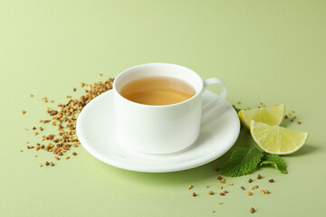 Concept of hot drink with buckwheat tea on green background