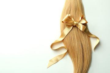 A lock of female hair with bow on white background