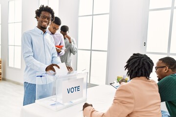 Group of young african american voter people putting vote in ballot standing at electoral center.
