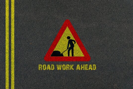 Road work ahead sign on black asphalt background, transportation and travel concept