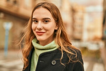 Young blonde girl smiling happy standing at the city.