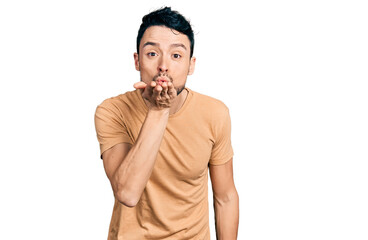 Hispanic man with beard wearing casual t shirt looking at the camera blowing a kiss with hand on air being lovely and sexy. love expression.
