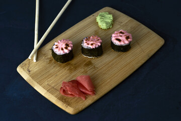 sushi and rolls on a wooden board with wasabi sticks and ginger