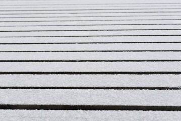 Snow-covered modern wooden pier (jetty, boardwalk) over the frozen river. Ice, frost, snow...